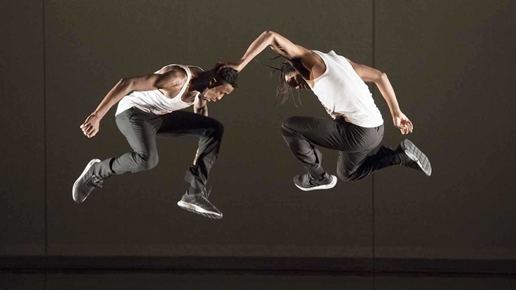 Dos chicos realizando un paso de hip hop en el aire.