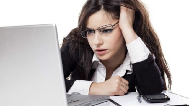 Chica viendo la pantalla de computador, con preocupación.