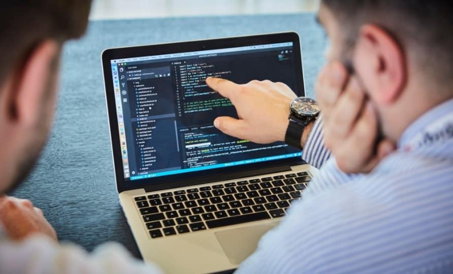 Profesor dictando clases de programación con un portátil.