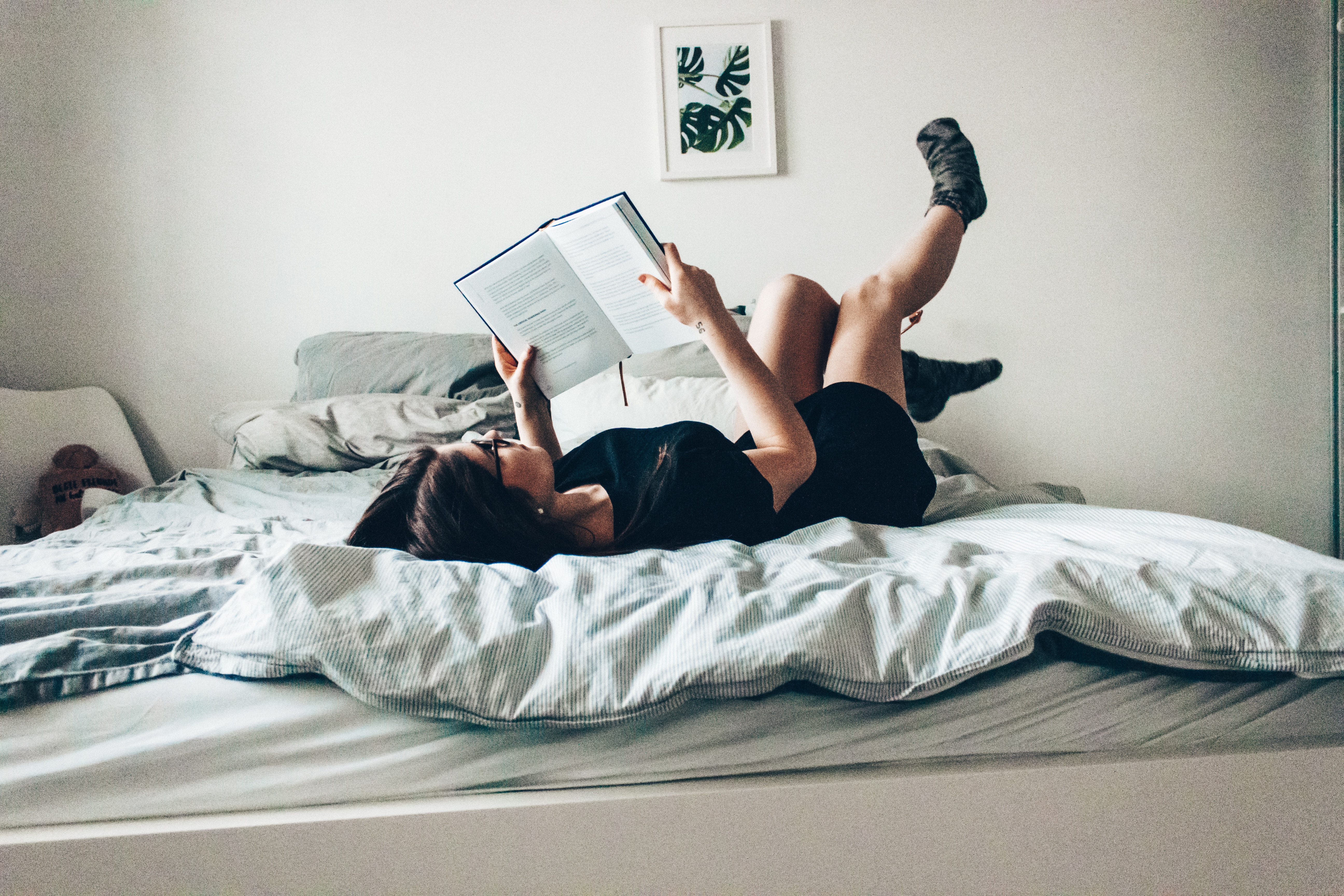 Mujer recostada en cama leyendo