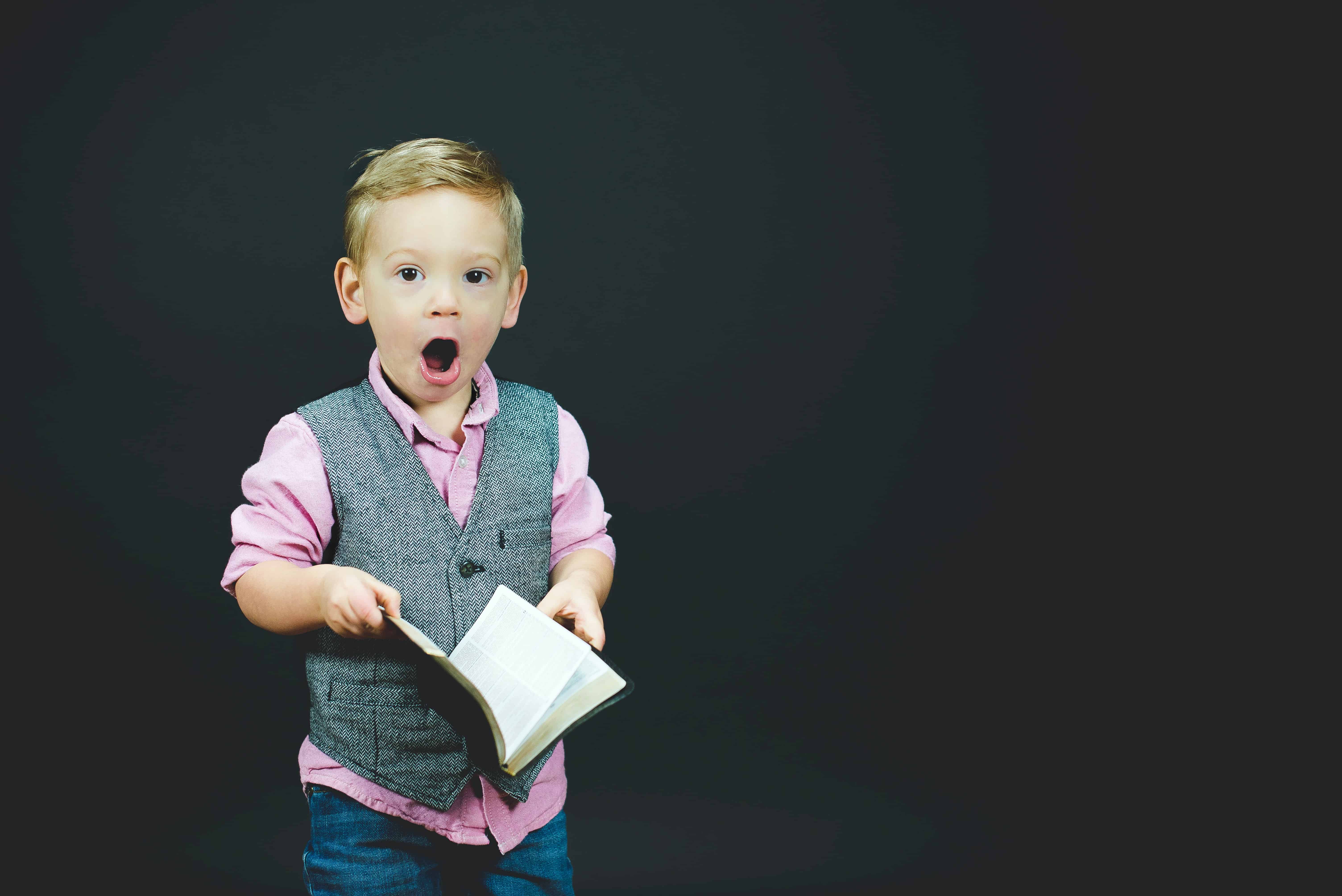 Niño sosteniendo un libro abierto y la boca totalmente abierta