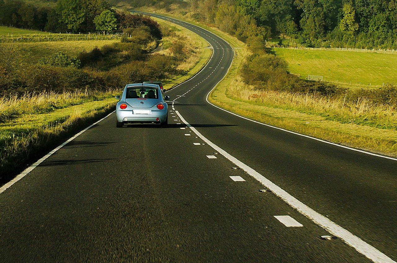 Auto, en una carretera que atraviesa un hermoso campo
