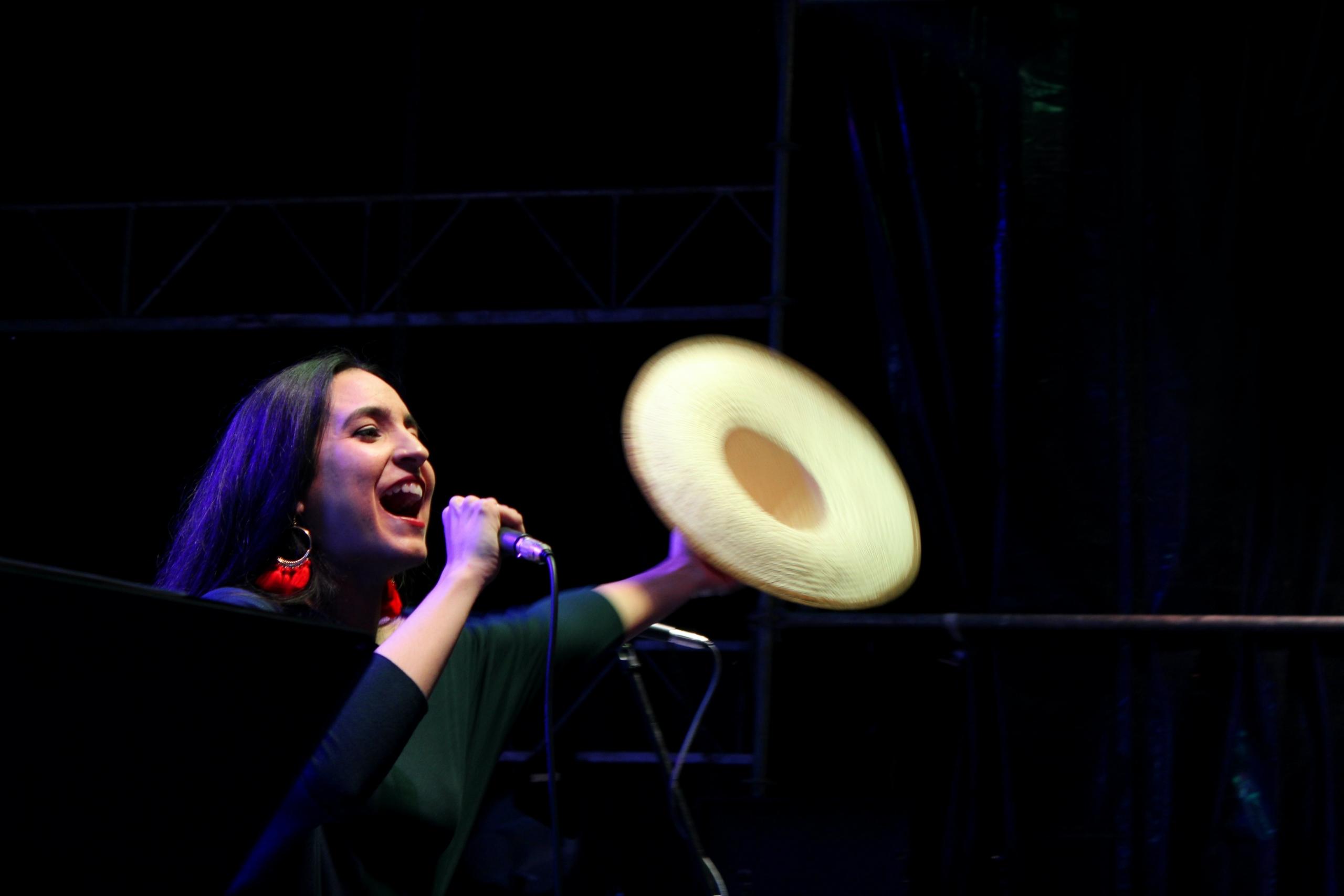 Mujer cantando al público sosteniendo un platillo