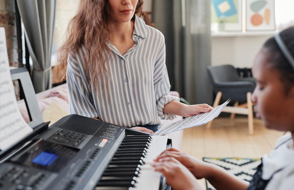 Profesora en una lección con alumna frente al teclado