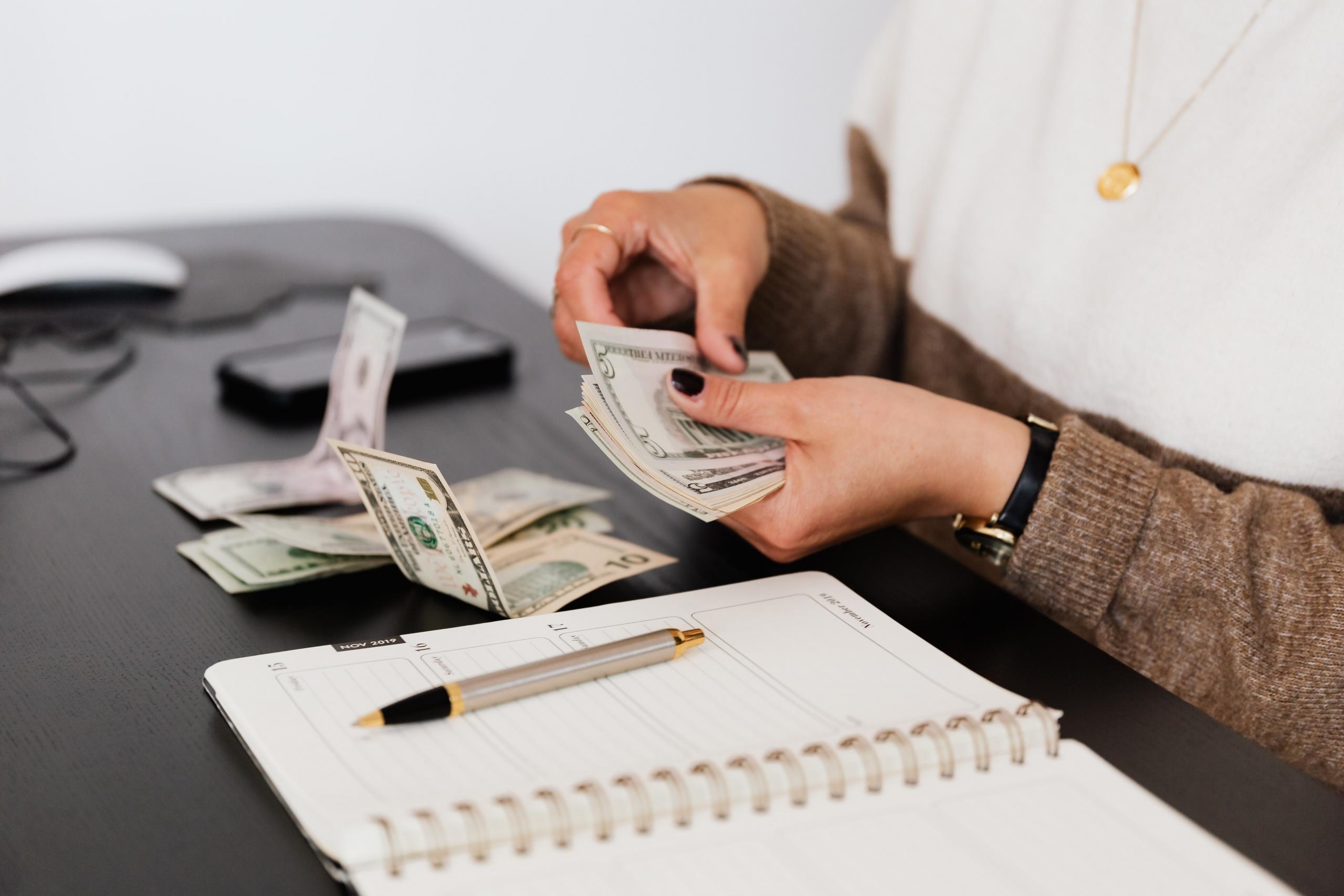 Mujer sentada en escritorio contando dinero