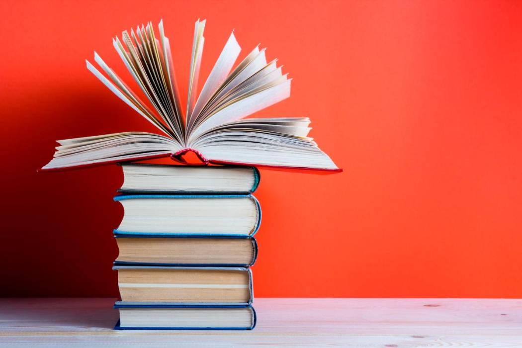 Pila de libros bajo un libro abierto.