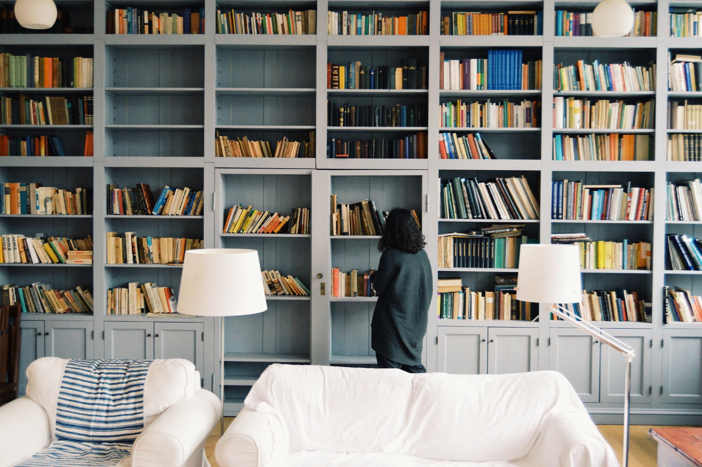 Chica escogiendo libros en una biblioteca.