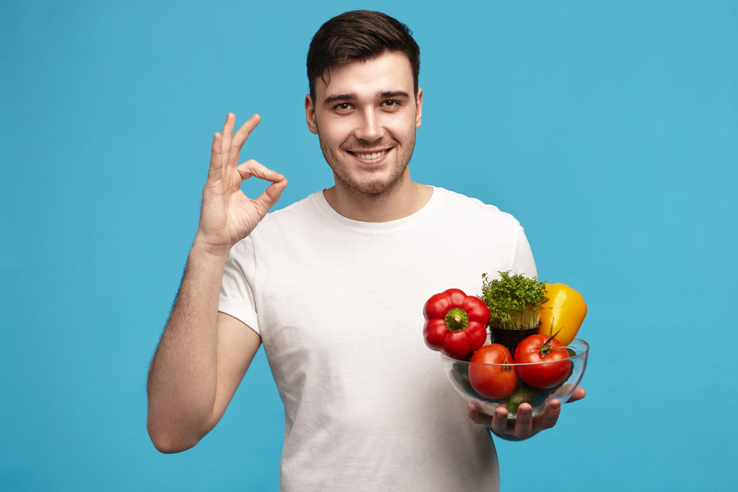 Joven alegre posando estudio con vegetales