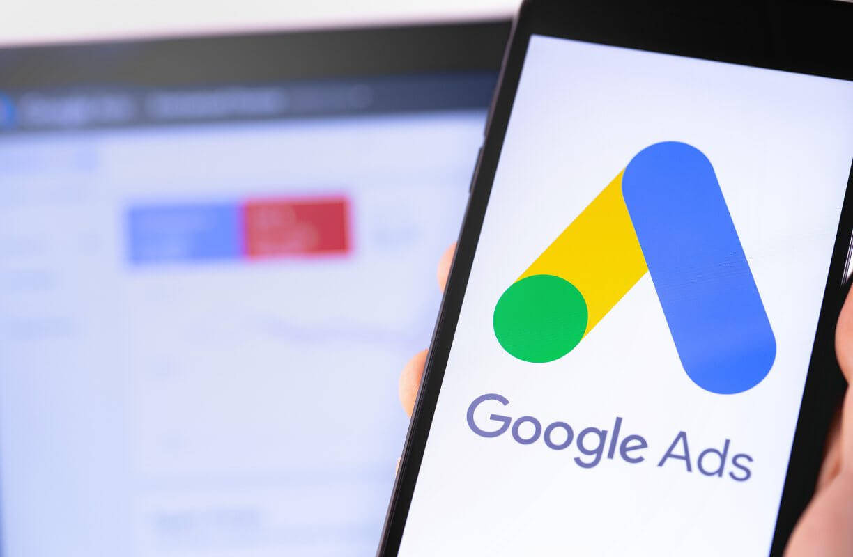 Logo de Google Ads. En la pantalla de un celular que alguien sostiene con una mano.