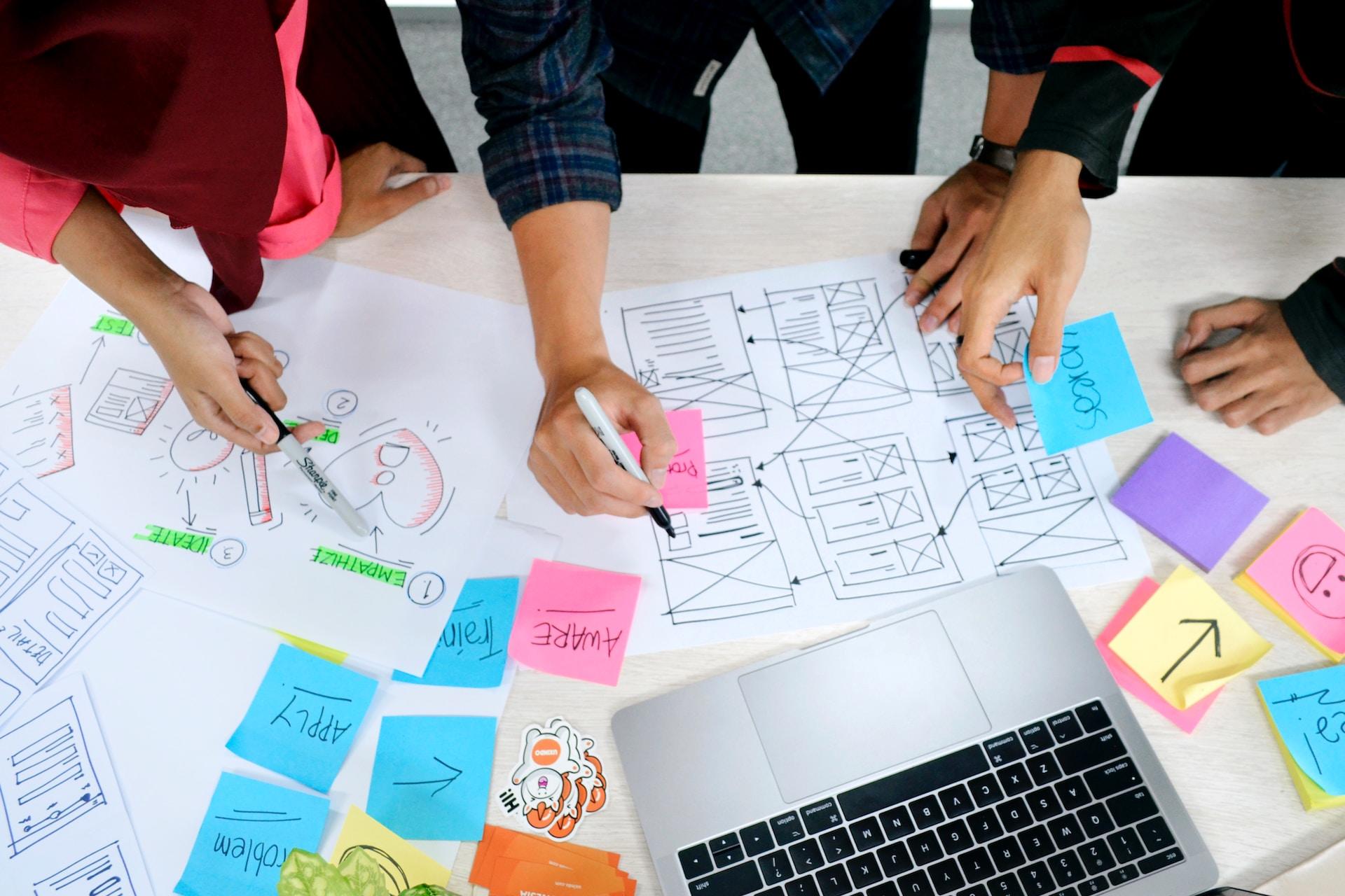 Personas realiza comparaciones, usando otras adhesivas y un portátil puesto sobre una mesa.