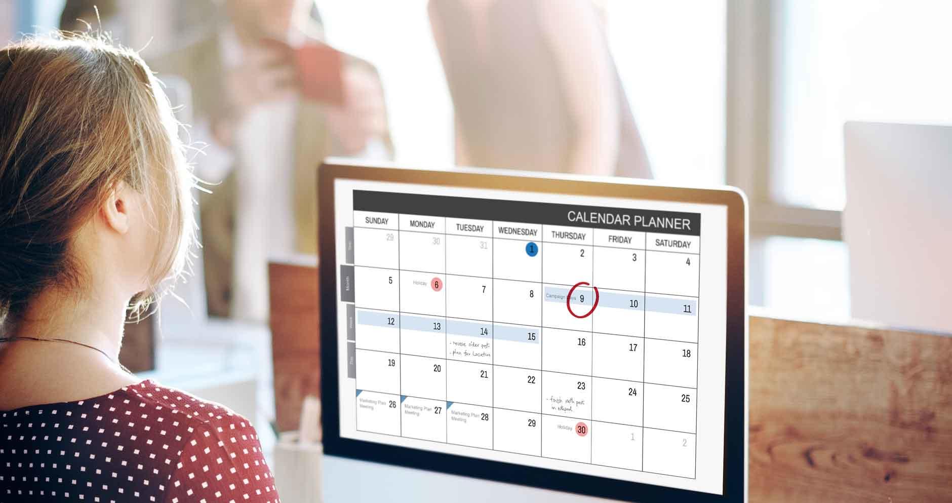 Chica viendo un calendario, que tiene algunas fechas resaltadas.