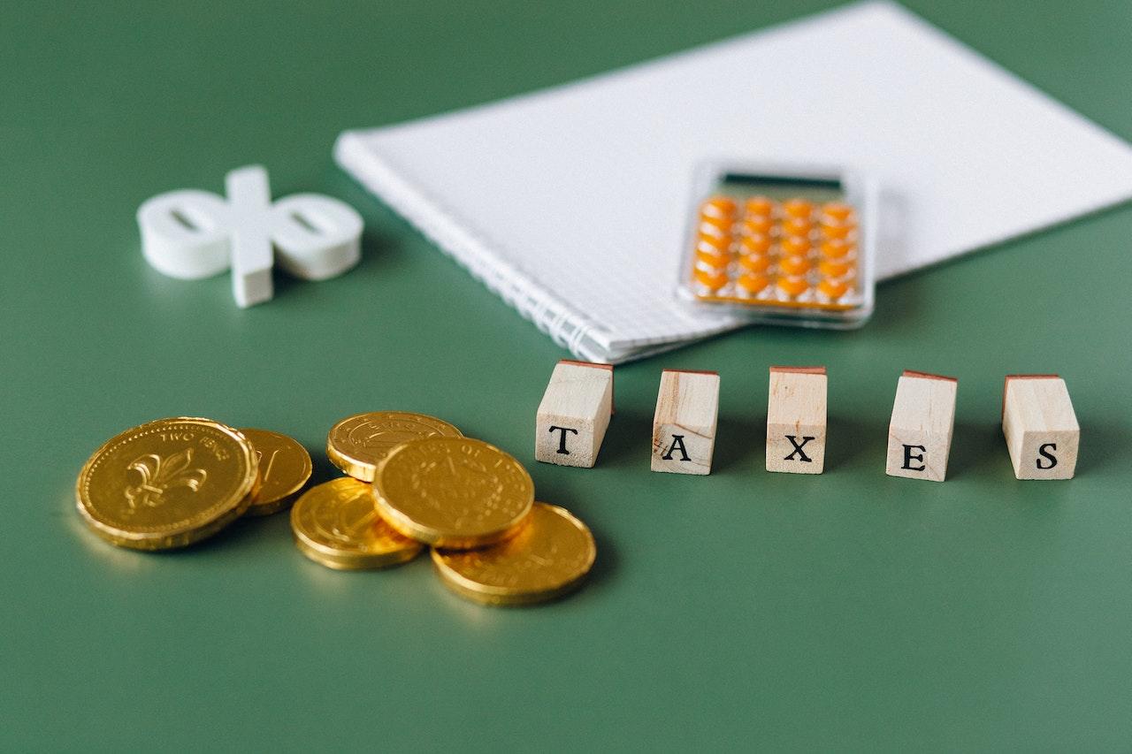 Monedas calculadoras símbolo de porcentaje y palabra TAX sobre una mesa.