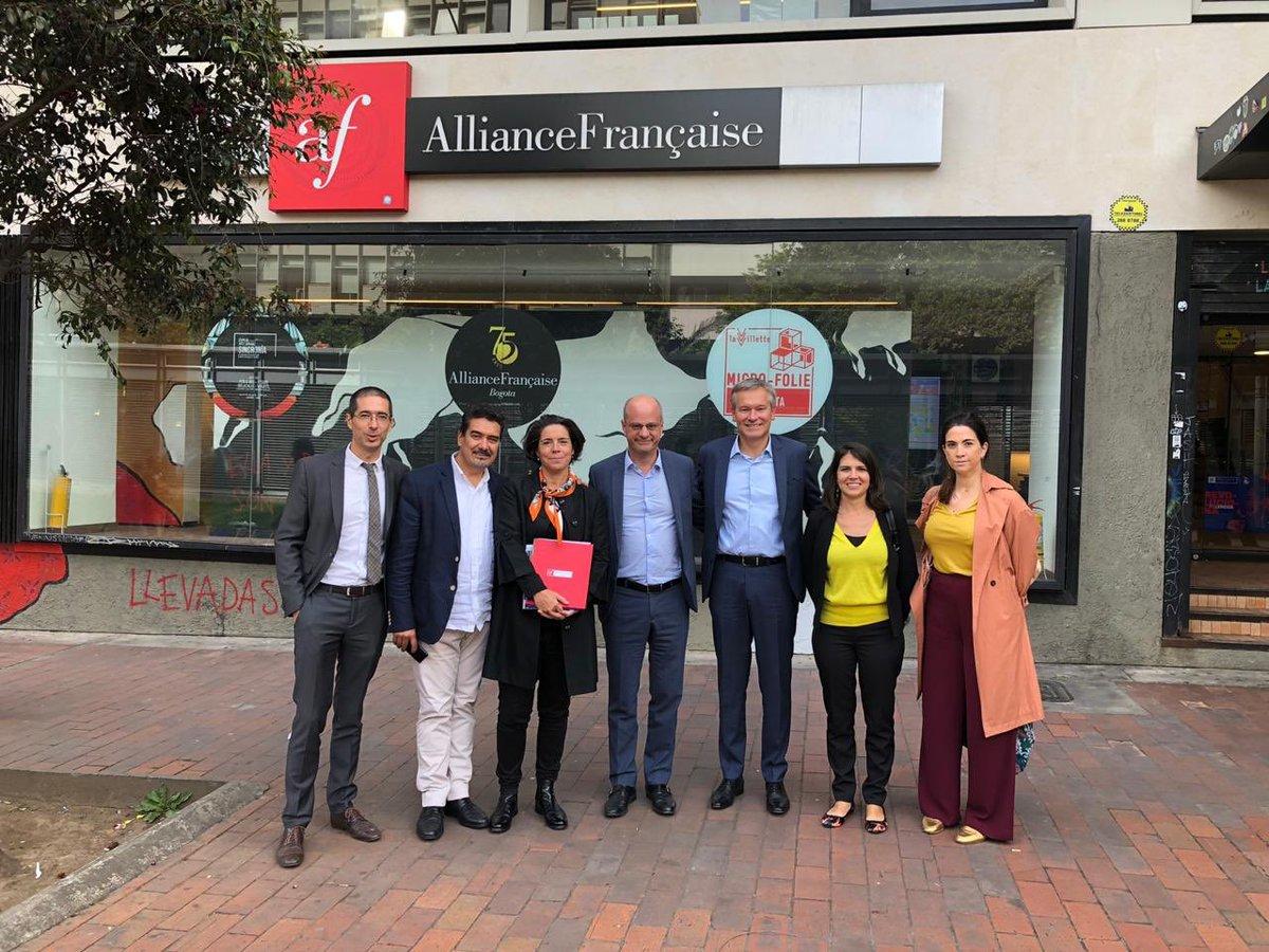 Grupo de personas de pie frente a una sede de la Alianza Francesa.