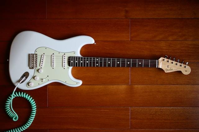 Guitarra Fender blanca sobre una superficie de madera