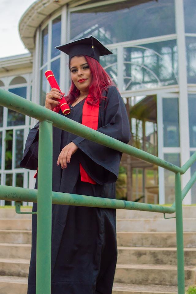 Chica vestida con toga y birrete sosteniendo un diploma