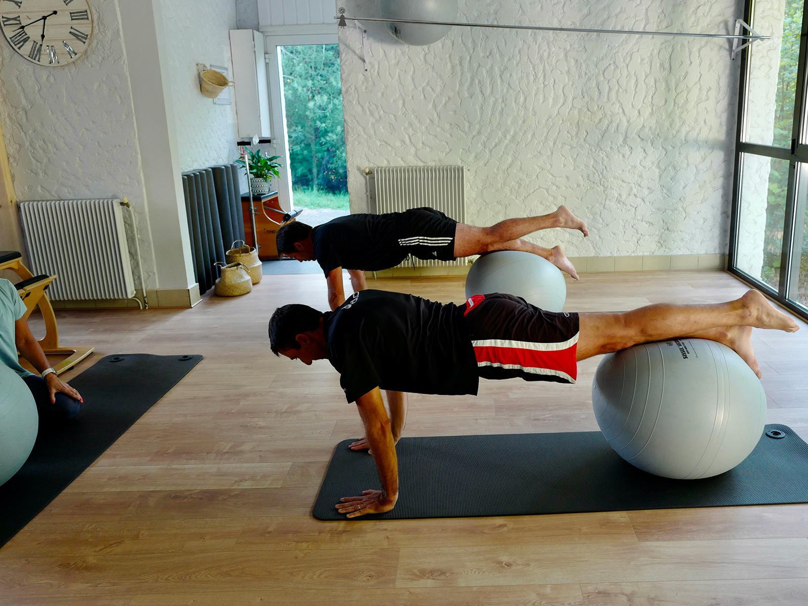 Dos hombres realizando pilates con la pelota fitness.