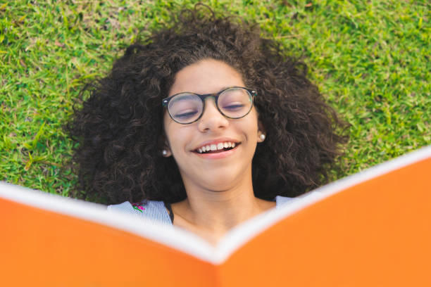Chica con cara de asombro mientras sostiene un libro cerca de su rostro.