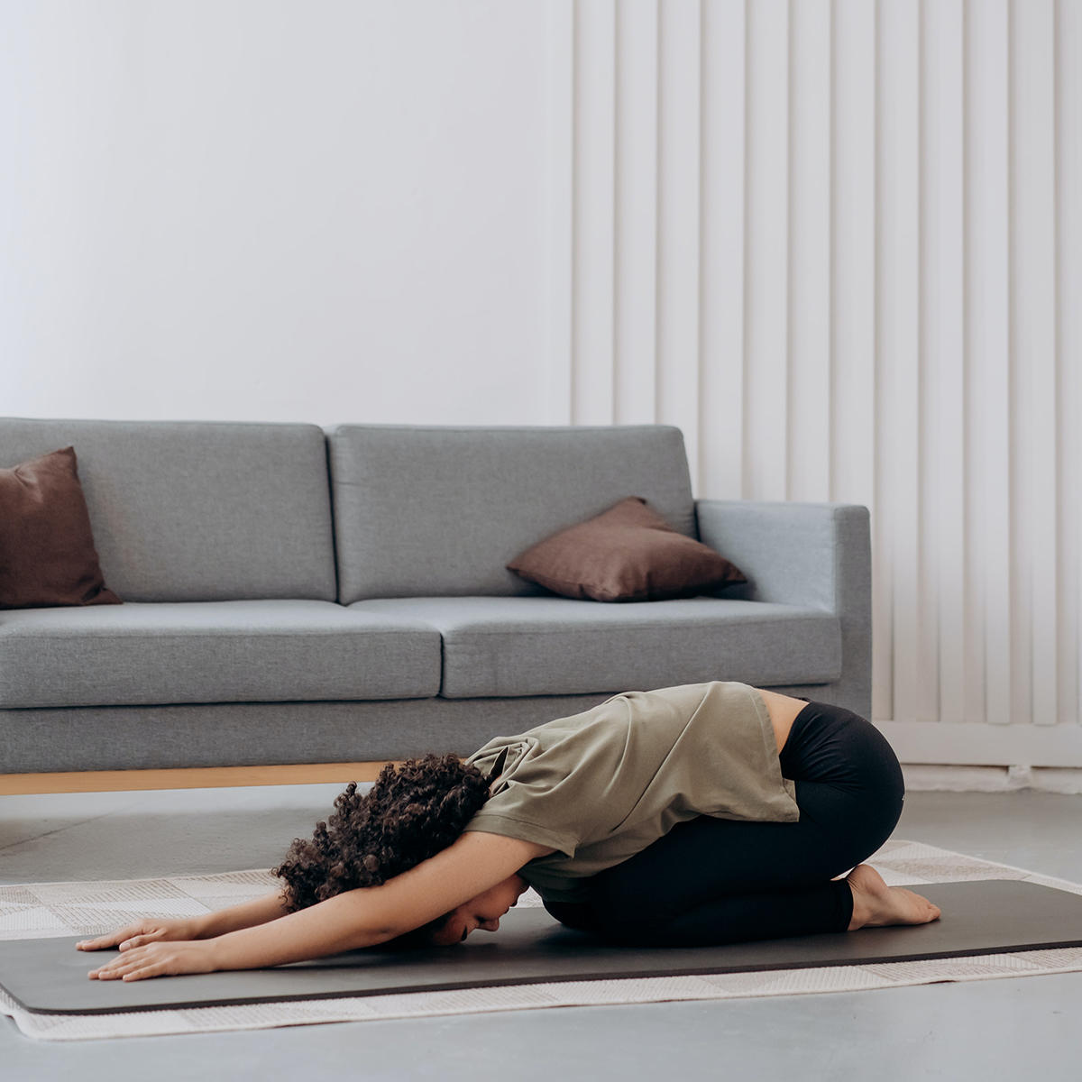 Chica realizando pilates en la sala de su casa.
