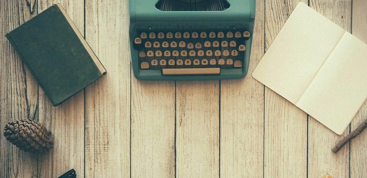 Máquina de escribir junto a un libro abierto y otro libro cerrado.