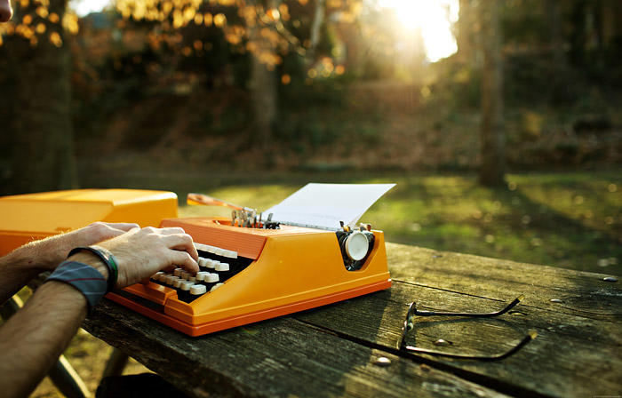 Persona usando una máquina de escribir en un parque.