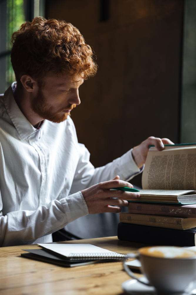 Hombre con barba extrayendo información de libros, tomando apuntes
