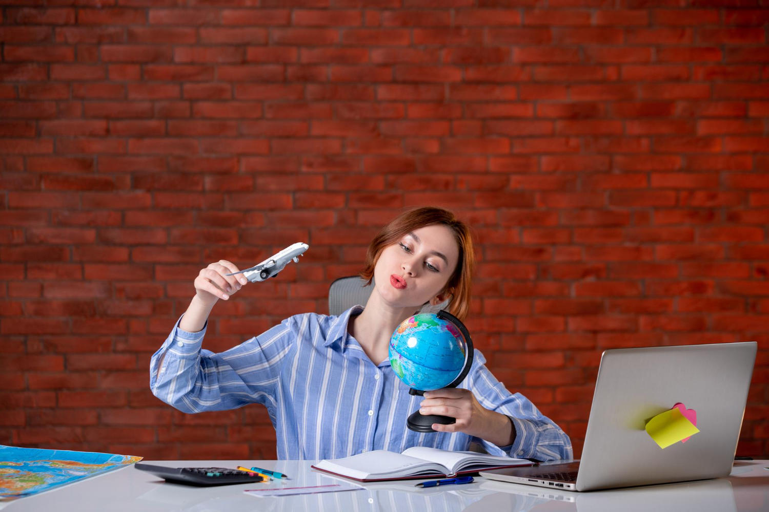Mujer rodeando con un avión miniatura un mapamundi que sostiene en la mano