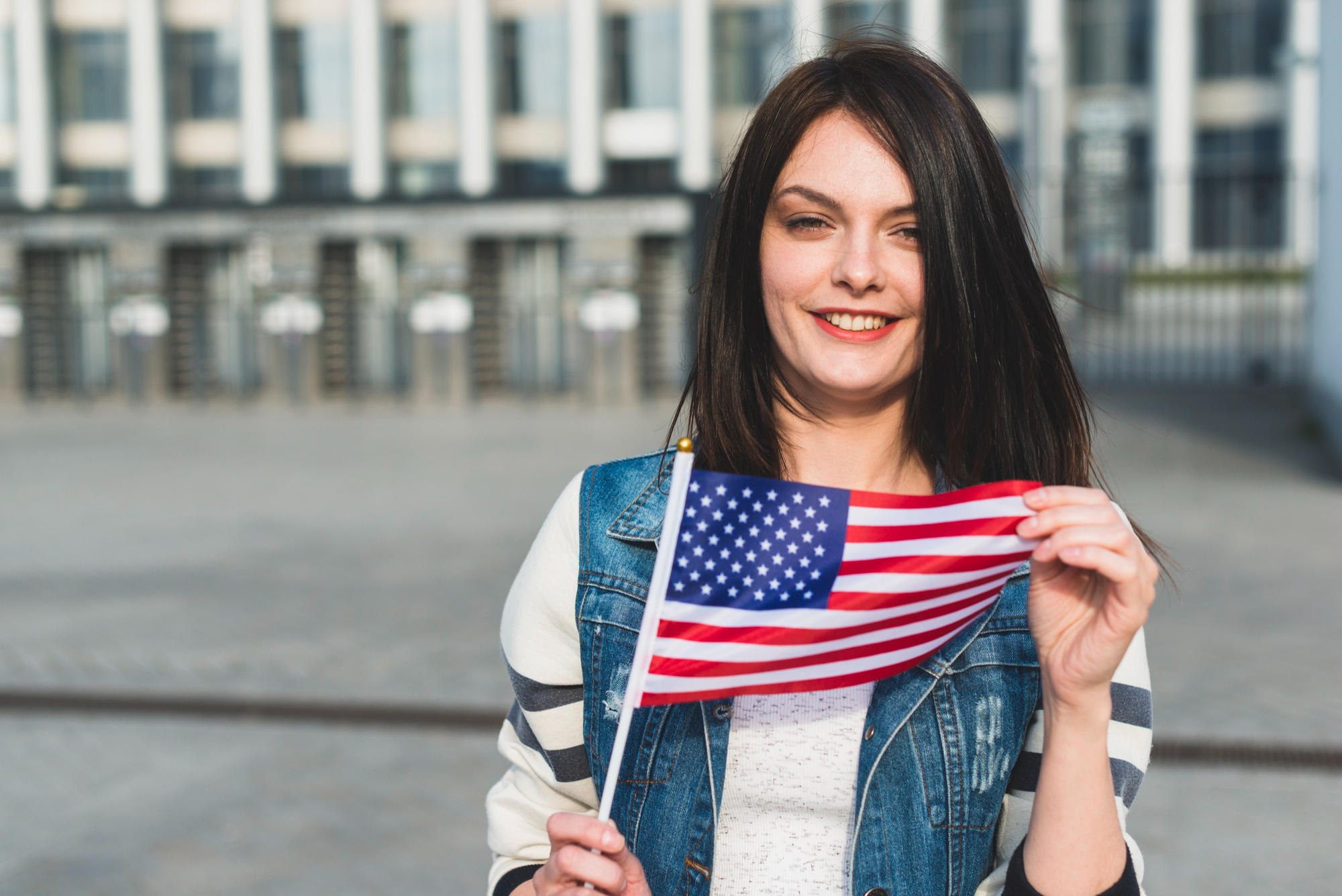 Chica a la salida de una universidad sosteniendo la bandera americana