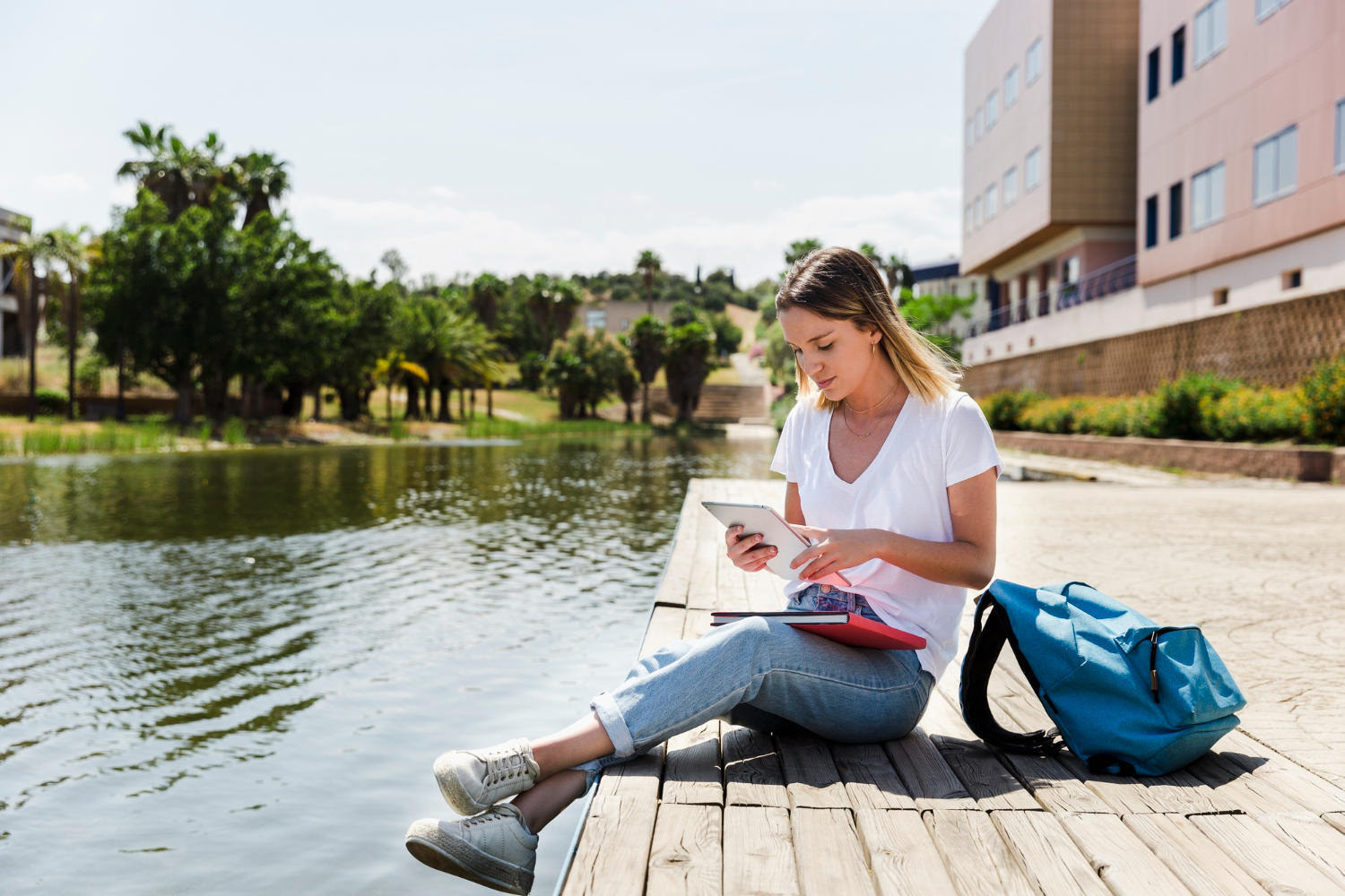 Mujer estudiando sentada a la orilla de un lago
