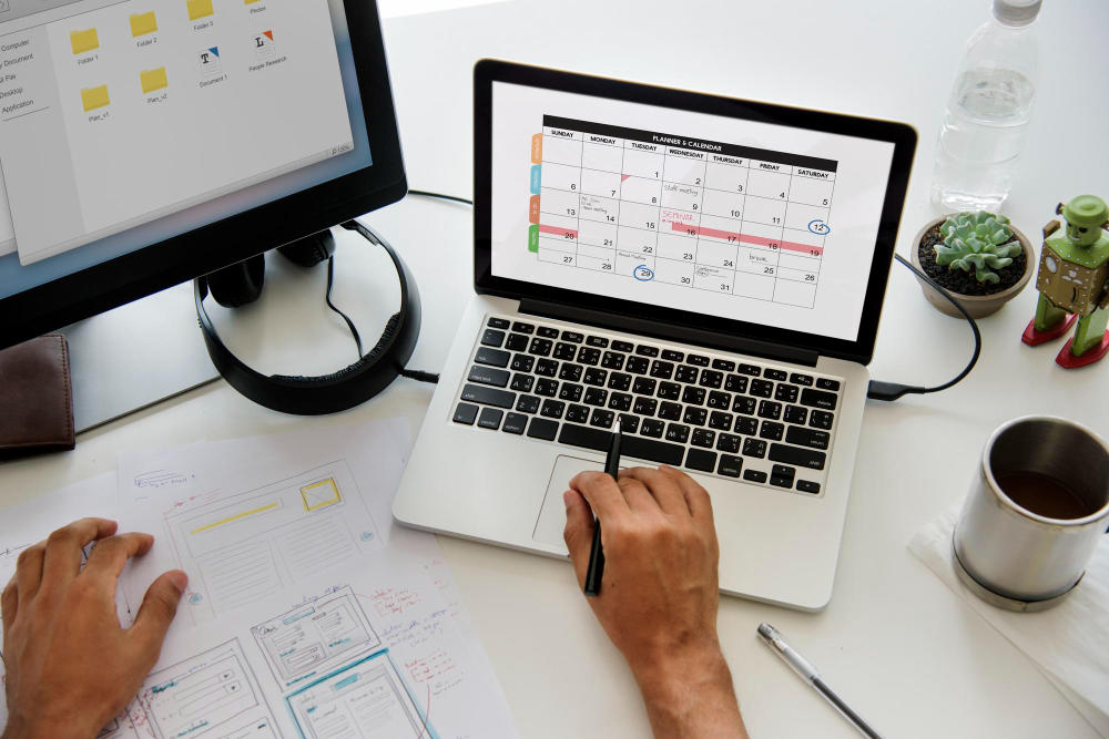 Mano en el teclado de una laptop que muestra un calendario en la pantalla
