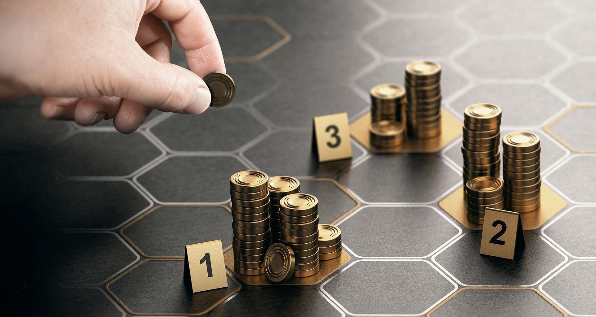 Mano colocando una moneda en una pila de monedas. Tres pilas de monedas sobre una mesa.