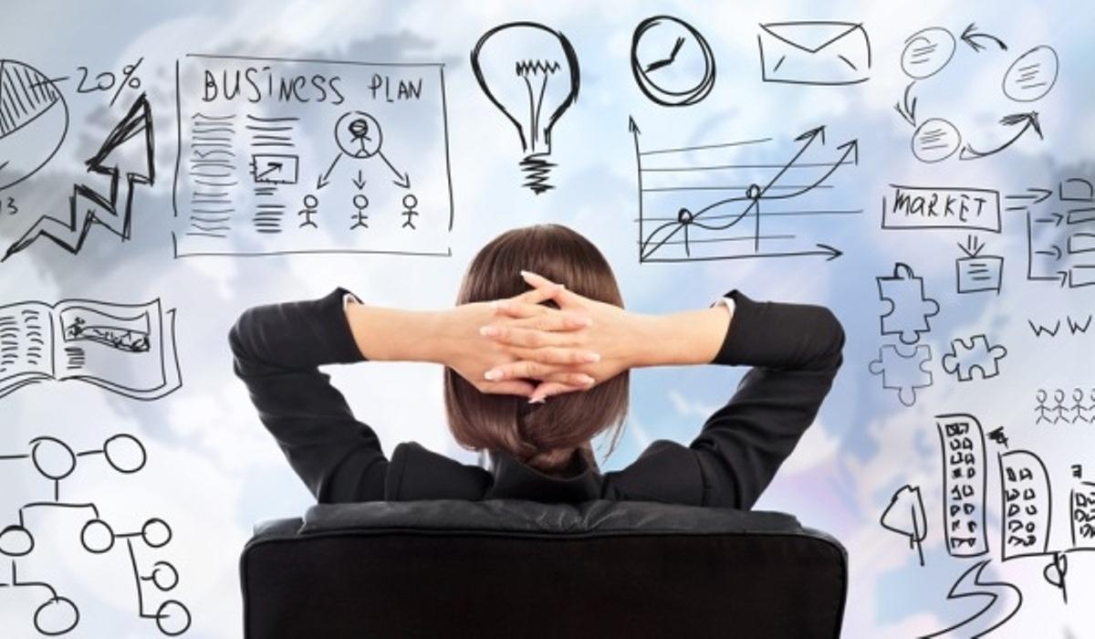 Chica sentada frente a un tablero trasparente que tiene varios iconos que le permiten analizar la creación de emprendimiento.