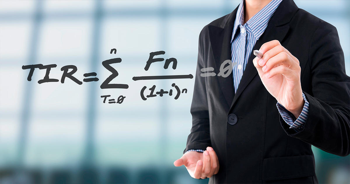 Profesor de matemática financiera escribiendo una fórmula en un tablero de cristal.