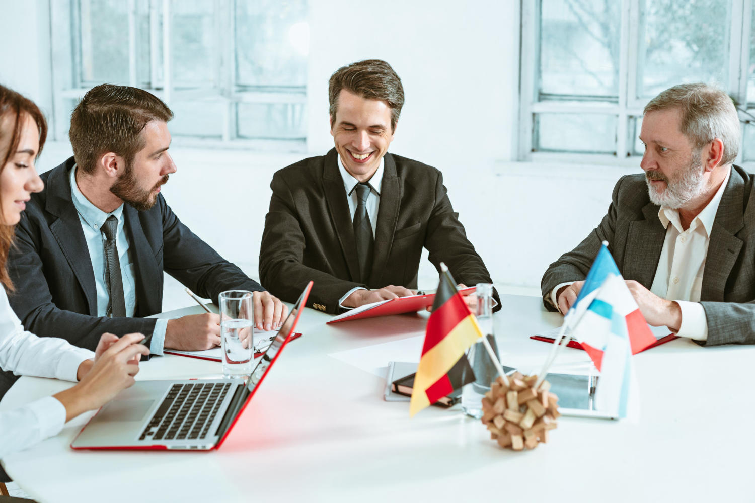 Varios trabajadores en junta de negocios, con una bandera de Alemania sobre la mesa