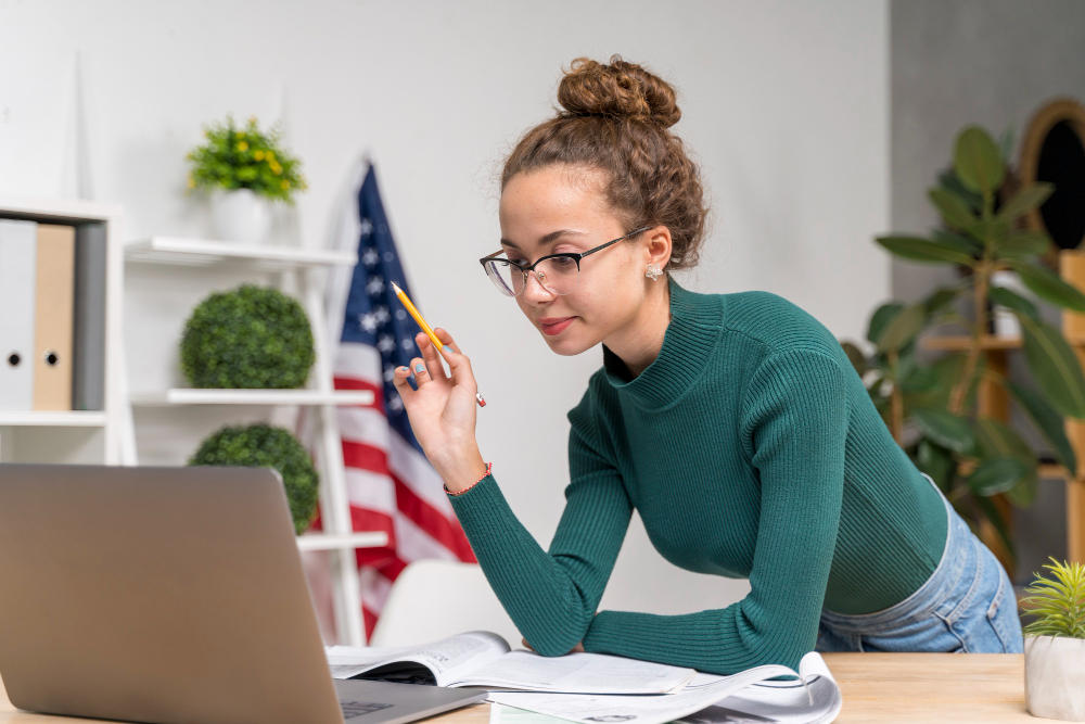 Chica haciendo examen en casa, atrás una bandera Americana