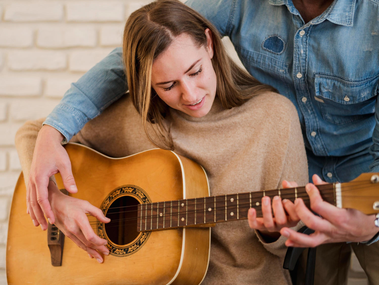Profesor corrigiendo postura de las manos a la alumna de guitarra