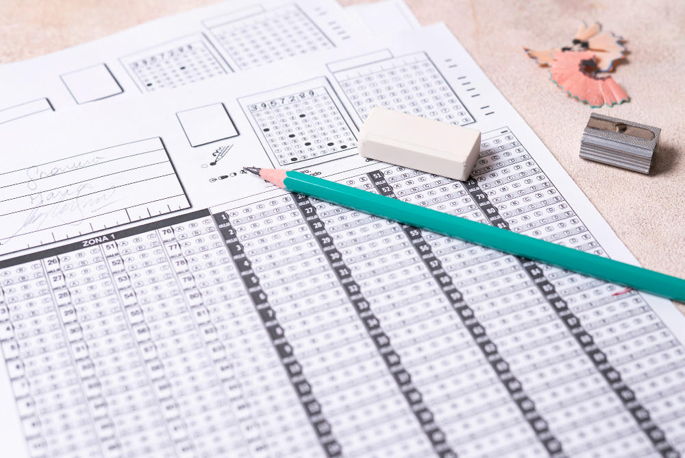 Hoja de respuestas de examen con un lápiz, borrador y tajalápiz