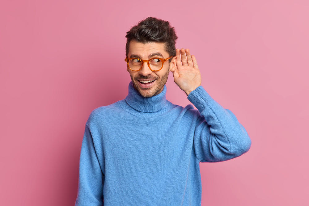 Hombre con la mano en la oreja tratando de escuchar