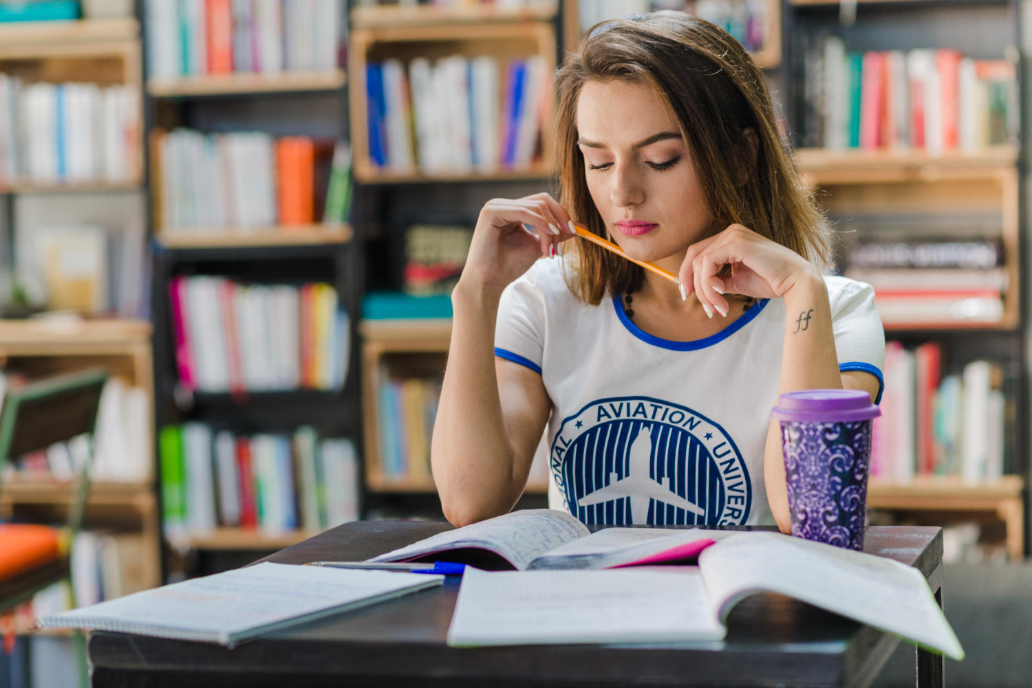 Mujer leyendo en una biblioteca, sosteniendo un lápiz con las manos
