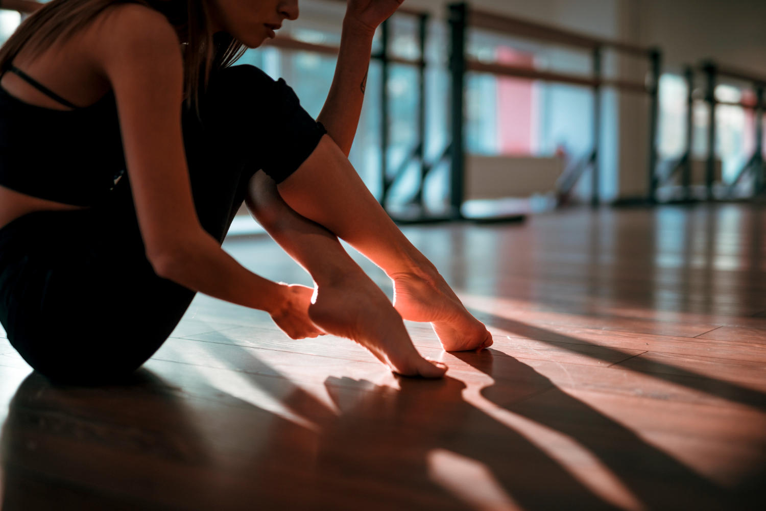Bailarina sentada en salón vacío tocándose los pies