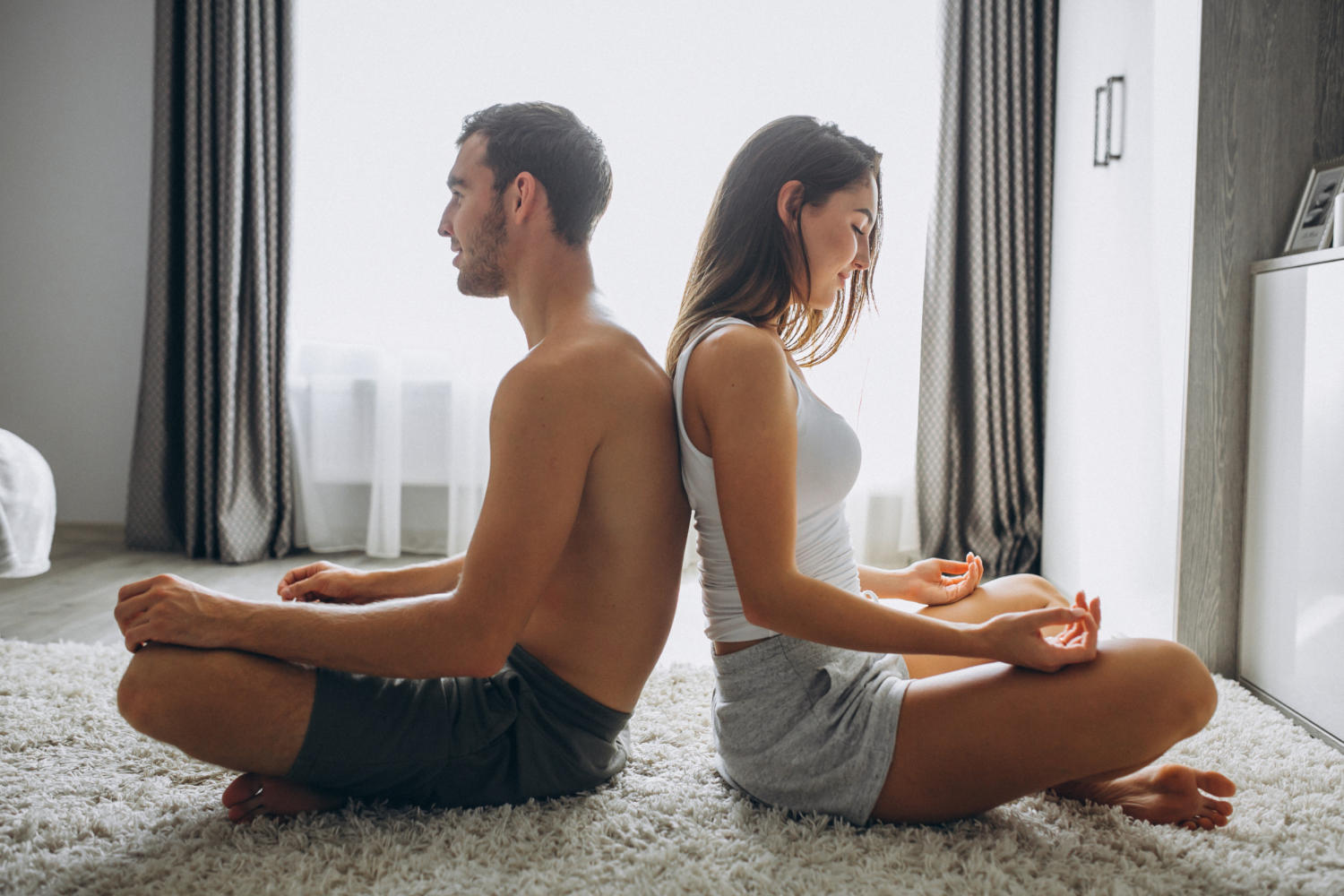 Pareja en posición de meditación apoyados espalda con espalda