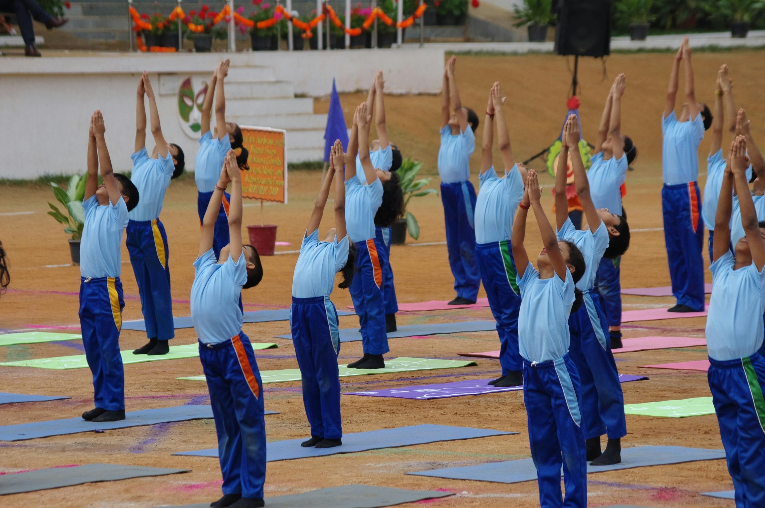 La imagen muestra a un grupo de estudiantes, vestidos con uniformes deportivos azules, participando en una clase de educación física en su colegio.