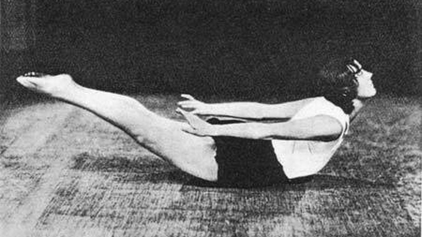 Una mujer realiza una postura sobre una alfombra