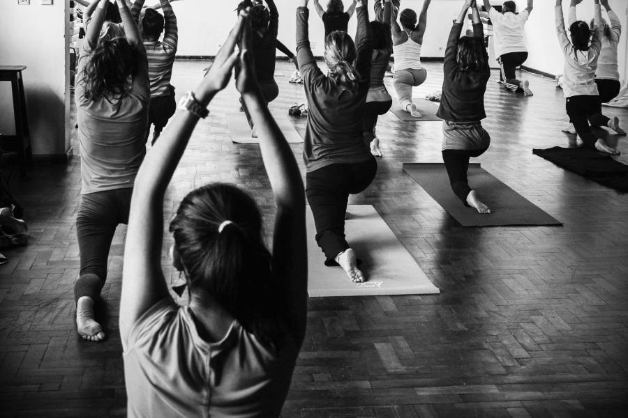 Varios estudiantes de yoga realizan una posición en la que están de rodillas sobre el suelo