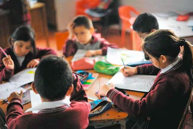 En una mesa redonda están sentados varios estudiantes