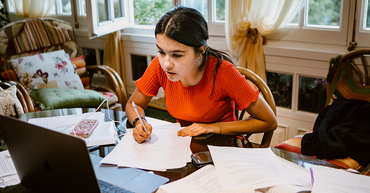 Una estudiante toma apuntes mientras está en una clase virtual