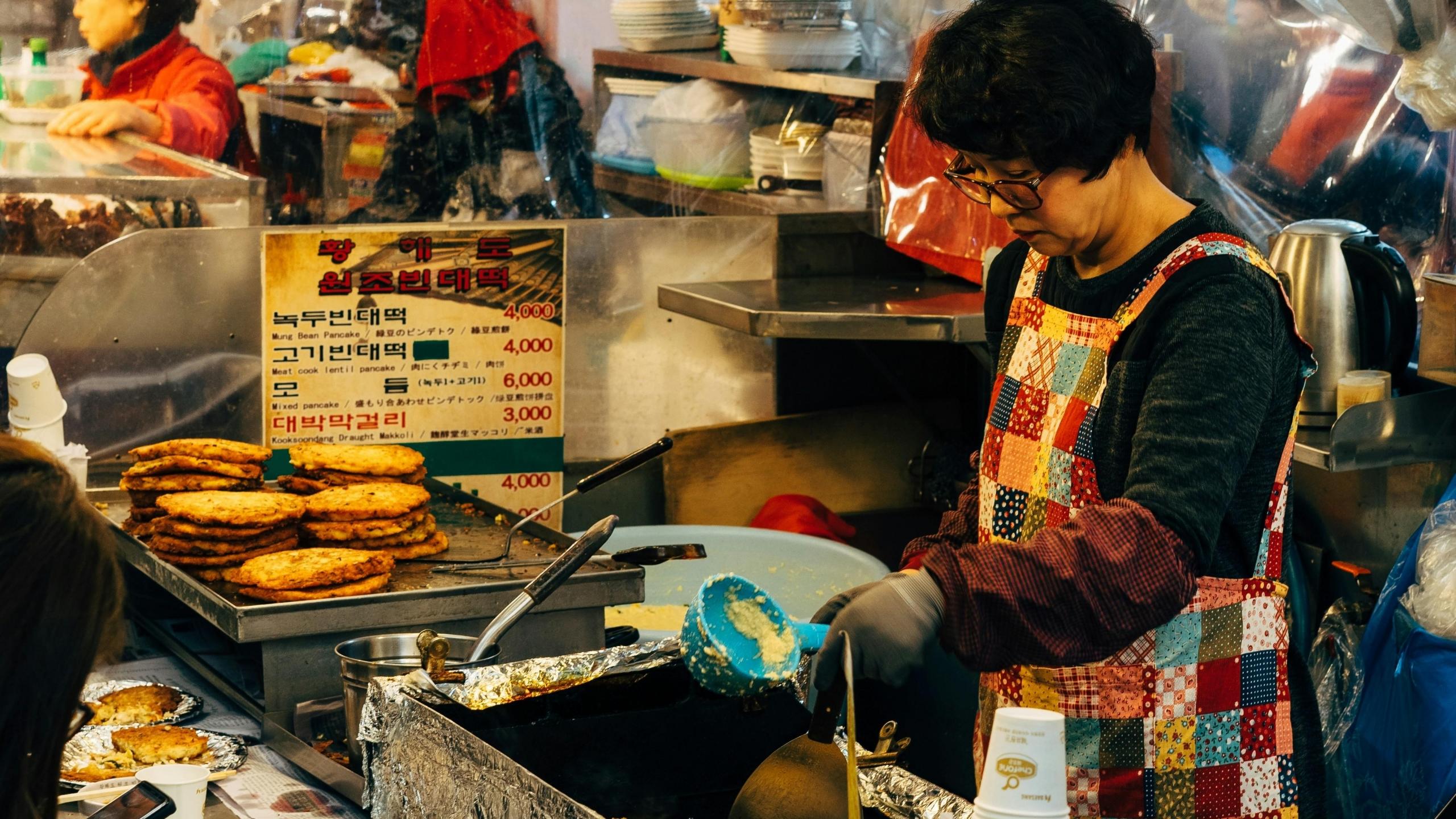 Imagen de mujer coreana preparando Hotteok, postre tradicional coreano