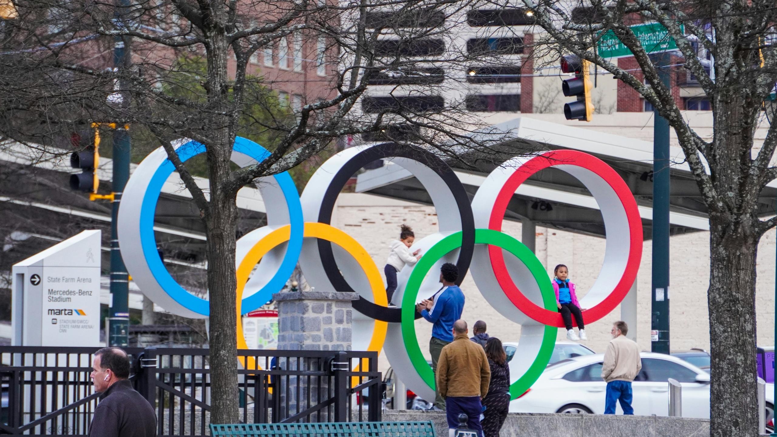 Imagen de niños jugando en una escultura de los aros emblemáticos de los juegos olimpicos
