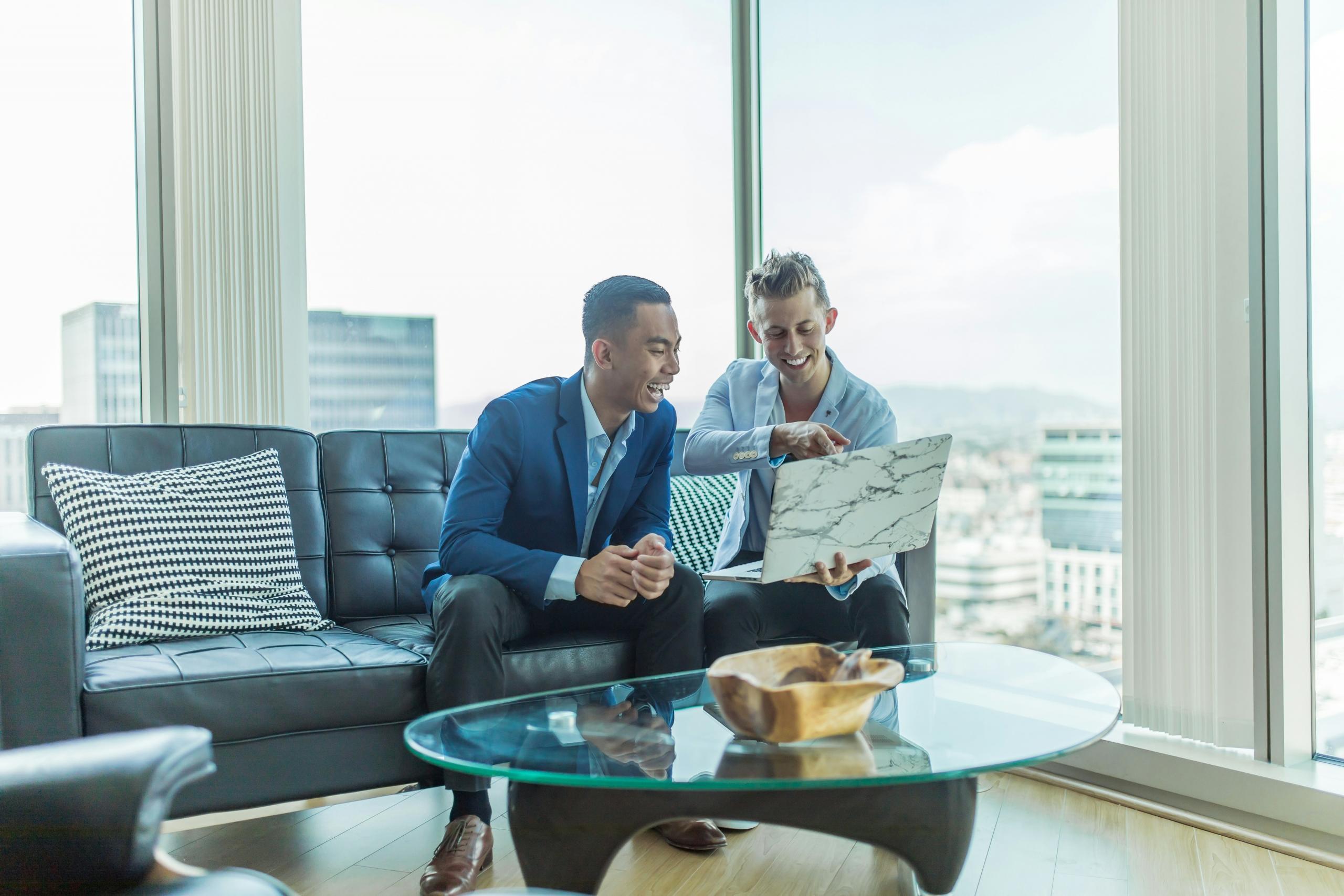 Dos hombres alegres viendo un computador portátil
