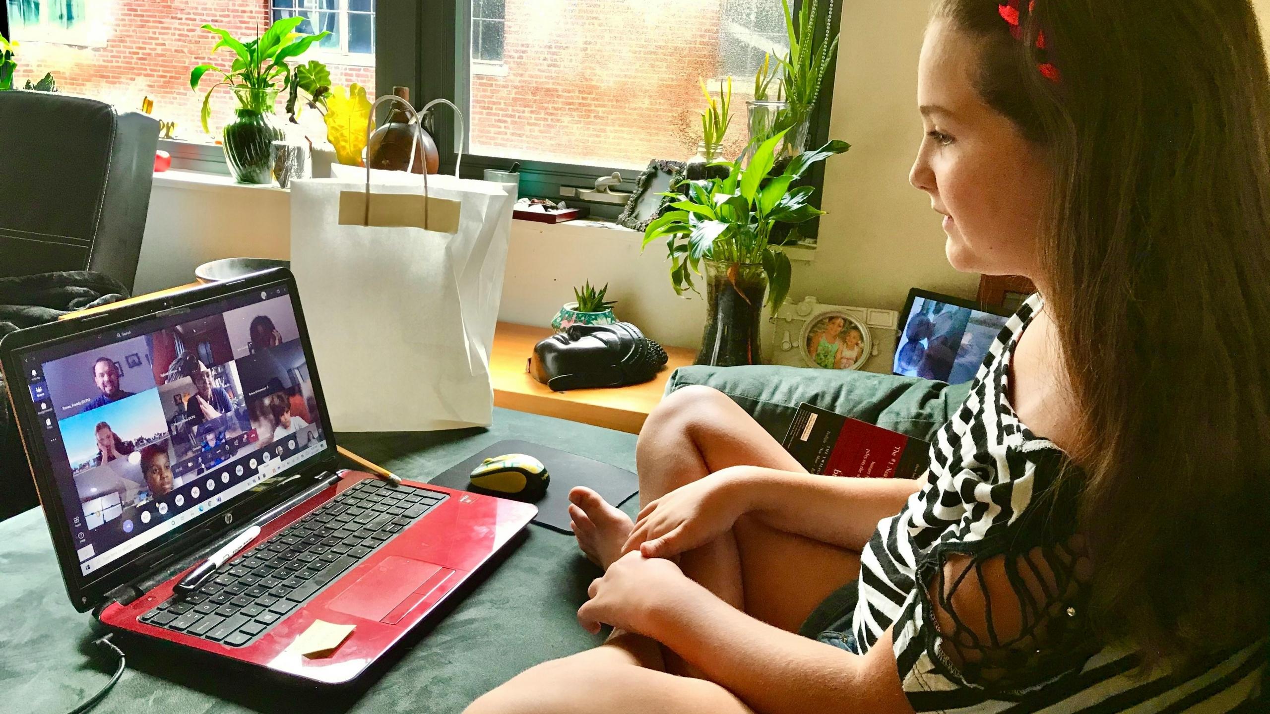 Mujer recibiendo una clase online compartida en su computador portatil en la sala de su casa
