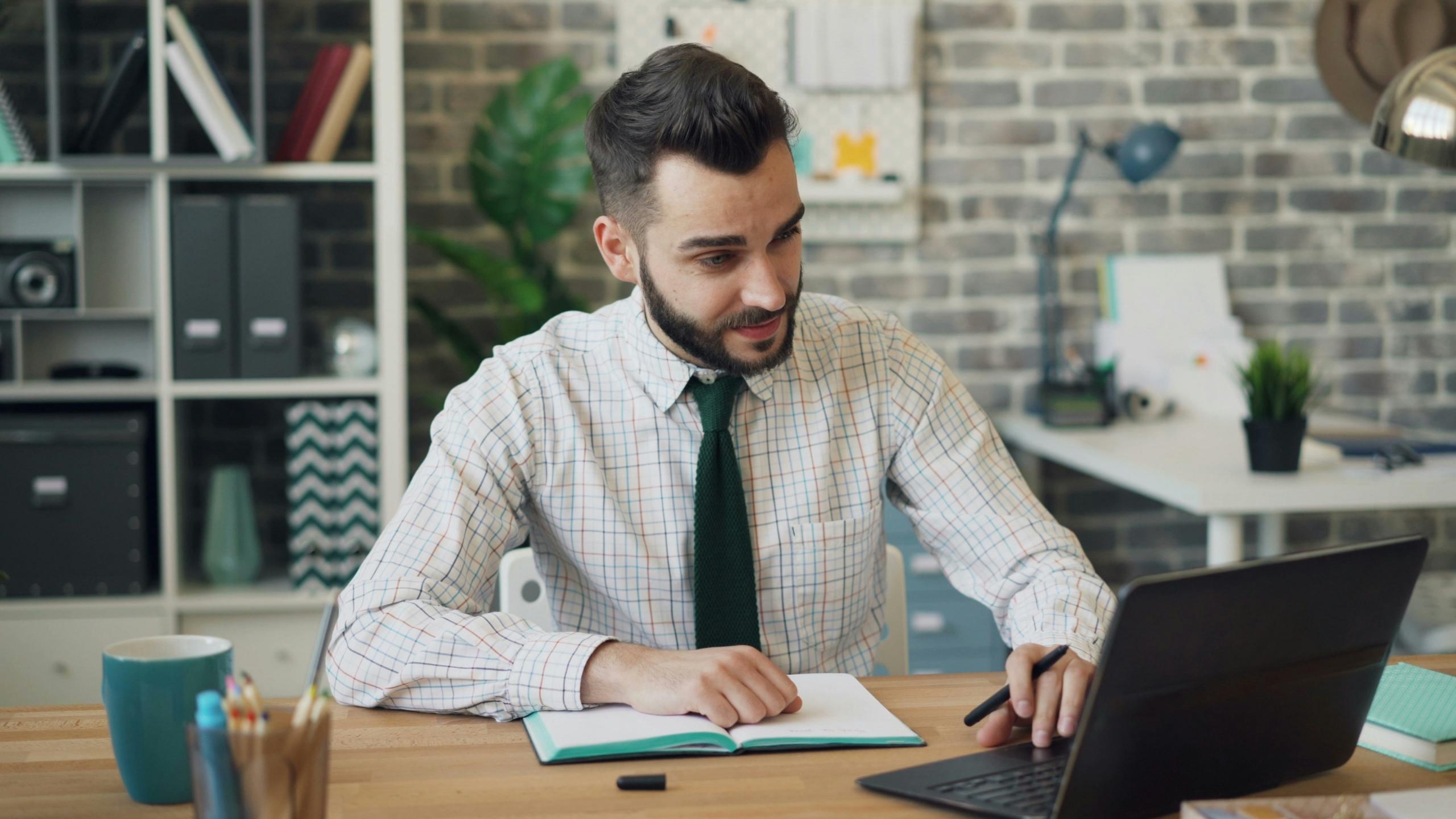 Hombre alegure, mira su tablet mientras revisa documentos de excel